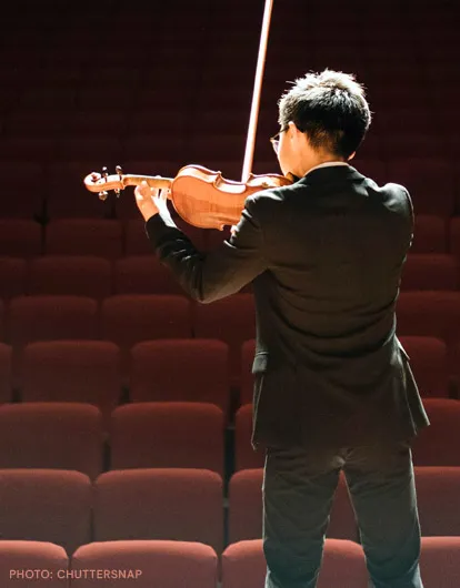 Photo of a violinist with a theater in the background